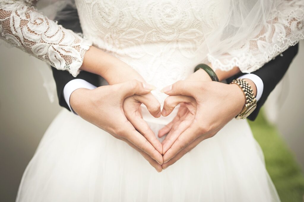 Pareja casada haciendo un corazón con las manos.